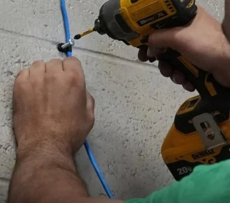 C&C tech securing low-voltage cable to a wall